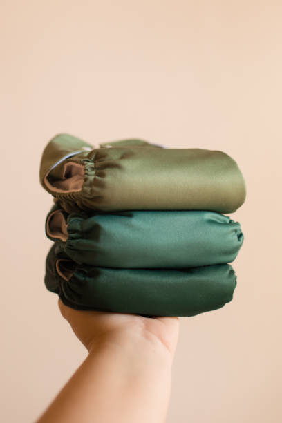 istock Female Hand Holding a Stack of Green Solid-Colored Reusable Cloth Diapers in Bright Natural Light 1289303574