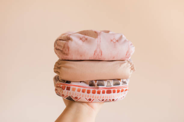 istock A Woman Holding a Stack of Modern Neutral-Colored Reusable Cloth Diapers with a Neutral Background in Bright Natural Light 1289303705