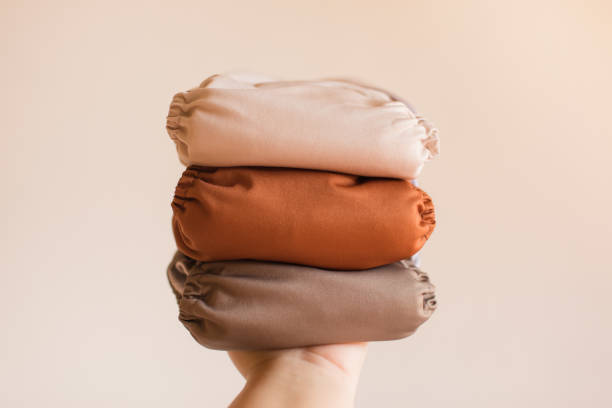 istock A Woman Holding a Stack of Modern Neutral-Colored Reusable Cloth Diapers with a Neutral Background in Bright Natural Light 1289303710