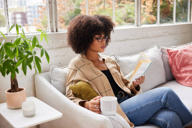 istock Young woman relaxing on her sofa with a book and a coffee 1289313249