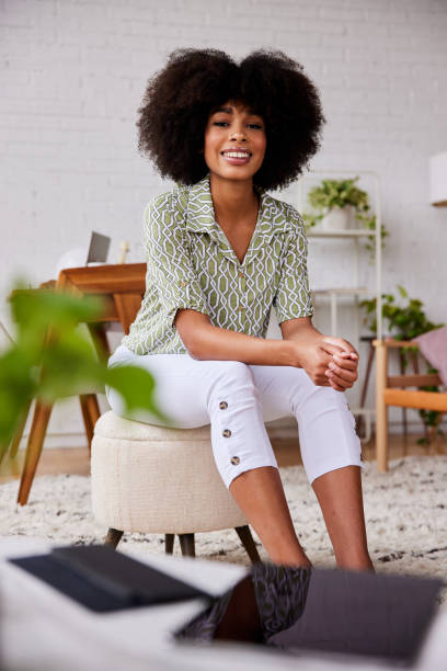 istock Smilling young woman sitting on a stool at home 1289314077