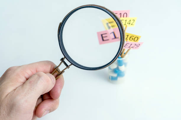 istock Food Additives E Ingredients Concept. Hand with a magnifying glass. Close-up white background. 1289314155