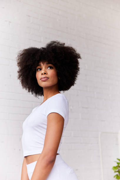istock Young woman glancing sideways against a white brick wall at home 1289314978