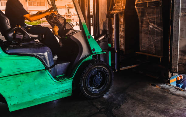 istock Worker driving forklift loading shipment carton boxes goods on wooden pallet at loading dock from container truck to warehouse cargo storage in freight logistics, transportation industrial, delivery 1289318318
