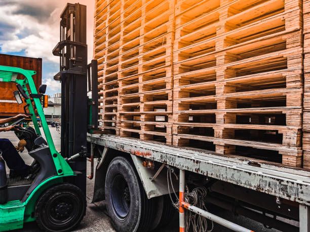 istock Worker driving forklift loading shipment carton boxes goods on wooden pallet at loading dock from container truck to warehouse cargo storage in freight logistics, transportation industrial, delivery 1289318324