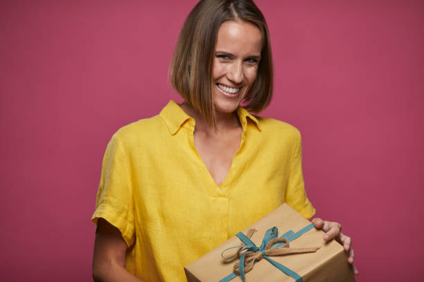 istock One woman holding a birthday gift and smiling. 1289321936