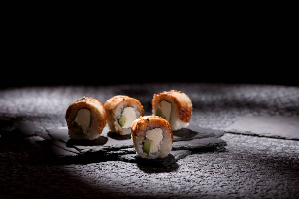 istock Appetizing rolls on a textured black background. Japanese food concept. Close-up. Copy space. 1289322294