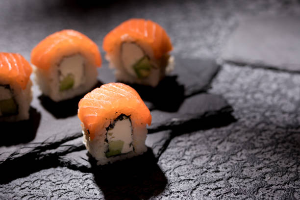 istock Appetizing rolls on a textured black background. Japanese food concept. Close-up. Copy space. 1289322844