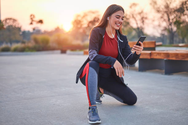istock Modern young woman with cellphone making pause during jogging / exercise. 1289326600