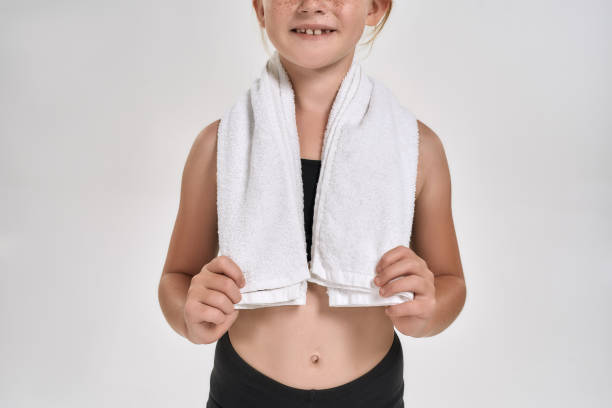 cropped shot of little sportive girl in sportswear smiling at camera, standing with white towel around her neck while posing isolated over white background - gymnastics smiling little girls only isolated on white imagens e fotografias de stock