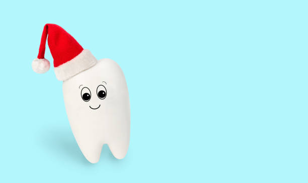 Fun toy white tooth in red Santa Claus hat isolated on light blue background. Festive concept for dentistry clinic. Christmas and New Year medical winter card, cute character for poster. Copy space. divertido diente blanco de juguete en sombrero rojo de santa claus aislado sobre fondo azul claro. concepto festivo para clínica de odontología. navidad y año nuevo tarjeta médica de invierno, carácter lindo para cartel, espacio de copia.