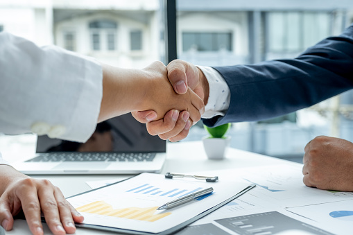 Shaking hands after businesswoman and businessmen team meeting to plan strategies to increase business income. Have a brainstorming graph analysis and discussing for the new target success.