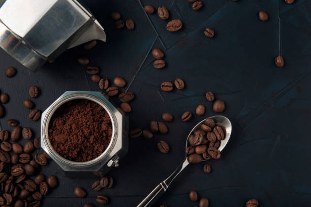 istock Metal spoon with coffee beans and coffee maker on the dark textured background. 1289331302