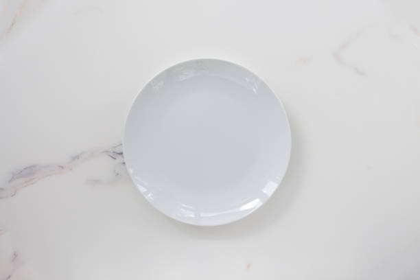 istock Empty ceramics plate isolated on white marble background. Copy space. Menu Recipe Concept 1289331373
