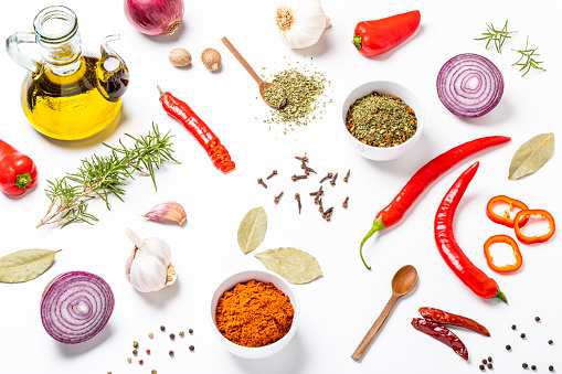 Vegan ingredients for seasoning: Olive oil bottle, spanish onion, chili peppers, garlic, some peppercorns, bay leaves, rosemary, chili powder, nutmeg and cloves on a flat lay white background. Studio shot taken with Canon EOS 6D Mark II and Canon EF 100 mm f/ 2.8\n\nSimilar images on my portfolio.