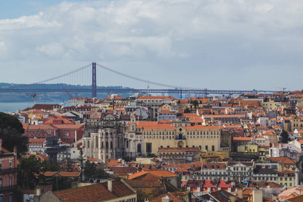 istock Lisbon. Bridge and Jesus Christ in background. Rooftops. Sunny spring day. 1289334455