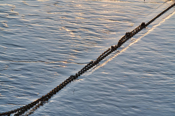 Metal linked chain in diagonal on wet sand in estuary