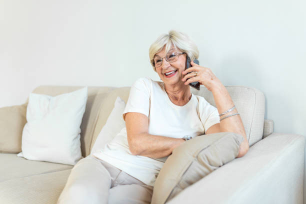 istock Beautiful Caucasian elderly female having phone conversation with her old friend using electronic device, discussing latest news with cute smile on her face, sitting at home 1289334877