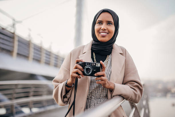 One woman, modern Muslim woman tourist with hijab, taking pictures with camera.