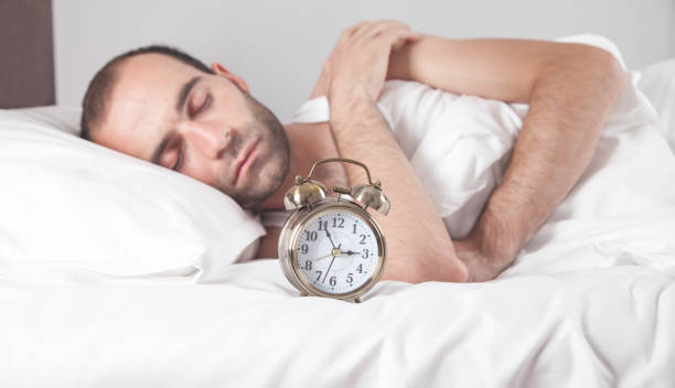 istock Man laying in bed with a alarm clock. 1289340665