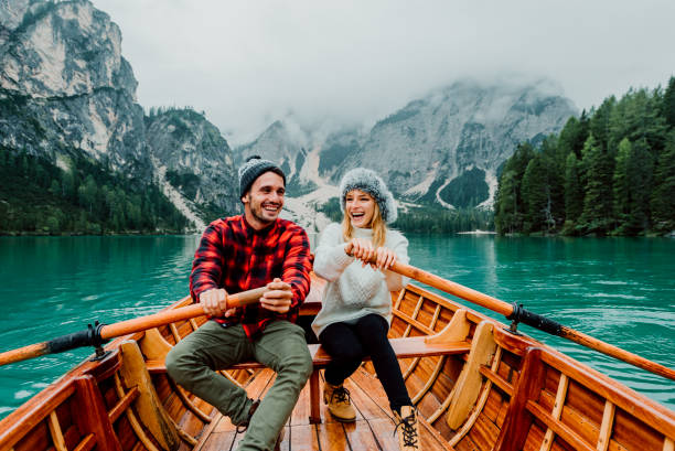 romantyczna para na łodzi odwiedzając alpejskie jezioro w braies włochy. turysta zakochany spędza kochający chwile razem w jesiennych górach. pojęcie o podróży, para i wanderust. - transportation mountain winter couple zdjęcia i obrazy z banku zdjęć