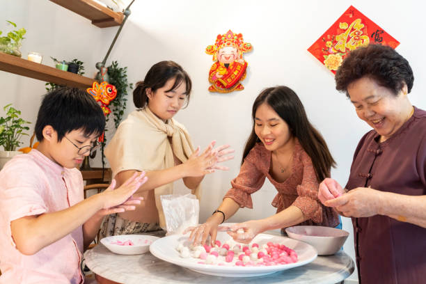 Making rice dumpling together on Chinese New Year Young Asian Chinese boy and girl enjoying making glutinous rice dumplings (Tang Yuan 湯圓) with senior grandmother in preparation for Chinese New Year reunion dinner celebration east asian ethnicity stock pictures, royalty-free photos & images