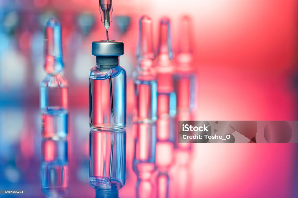 Vaccine in laboratory - flu shot and Covid-19 vaccination Close up shot of vaccines - glass bottles, ampules and syringe with needle. Good for illustration of flu shot, vaccination and covid-19 Vaccination Stock Photo