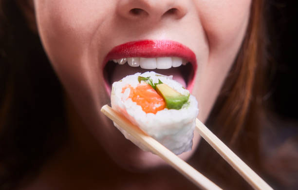 giovane donna bocca mangiare pezzo di sushi sulle bacchette - temaki food sushi salmon foto e immagini stock