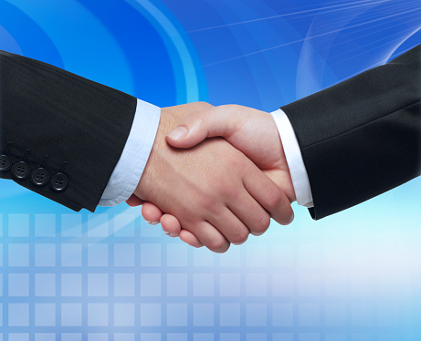 Two businessmen shake hands on the background of modern furnished office, deal concept, close up