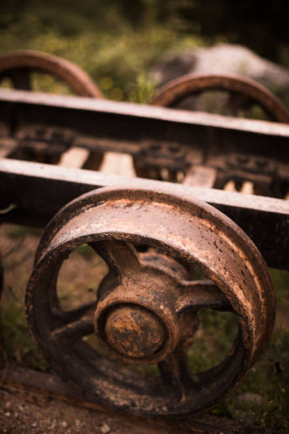 Close up shot of the rusty metal wheels of an abandoned wagon.