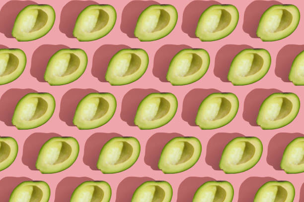 istock Trending style pattern of half seedless green avocado on pink background with hard light. Creative food texture. 1289346889