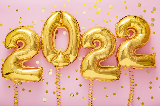 globos de oro de 2022 años en cintas con confeti en la pared rosa. feliz año nuevo 2022 celebración de la víspera - globo decoración fotos fotografías e imágenes de stock