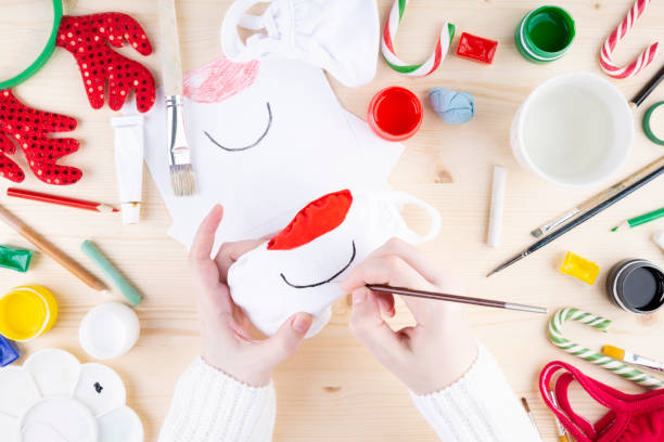 istock Diy festive pattern on protective mask. Step 2 painting on cloth mask deer face with red nose 1289349716