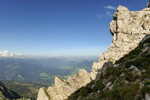 istock A panoramic view from an Alpine top on a vast valley. There are sharp mountains and high peaks around. The Alpine slopes are almost barren. Lush green valley. Bright day. Serenity and freedom. 1289351357