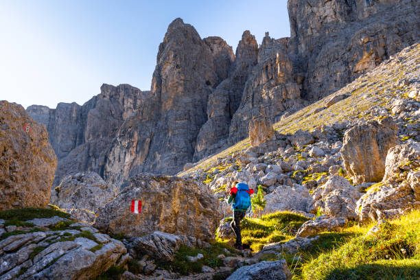 Young woman tourist mountaineer walking hiking rocky Alta Via trail under crag cliffs, backpacking Val de Setus South Tyrol, Italy tourism, travel Europe nature.