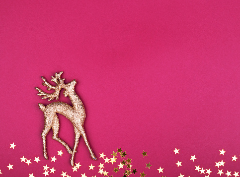 Shiny gold deer ornament and gold stars, with copy space, on a purple background. the Christmas symbol is a deer. deer team