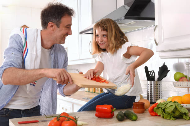 istock Happy father and daughter looking knowingly cooking at home 1289355846