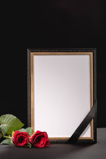 istock two red roses and mirror with ribbon on black background, funeral concept 1289357502