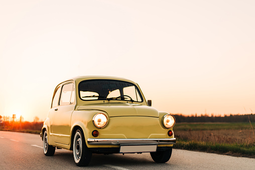 Oldtimer car Fiat 500 (Zastava), cute yellow car photo shoot during the sunset.