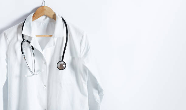 белое пальто доктора со стетоскопом на вешалке над белым фоном с копировальной площадью. - coat стоковые фото и изображения