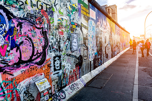 Berlin, Germany – July 08, 2019: The Berlin Wall with graffiti writings against the background of green trees and buildings