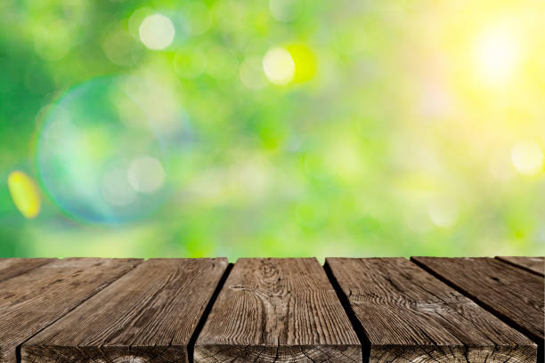 Empty rustic wooden table with defocused yellowish lush foliage at background. Ideal for product display on top of the table. Predominant colors are green, yellow and brown. XXXL 42Mp outdoors photo taken with SONY A7rII and Zeiss Batis 40mm F2.0 CF