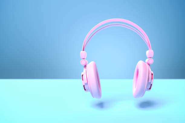 istock Music concept: A pink headphone against a blue background with shadow. Copy space - selective focus on foreground 1289363041