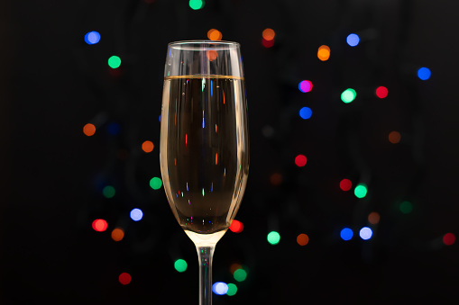Christmas and New Year celebration with champagne. Champagne glass with colorful dots background