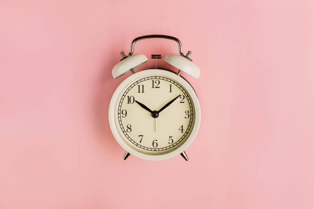 istock Old school white alarm clock on the pink background. 1289366190