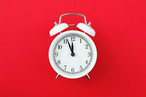 istock Alarm clock showing five minutes to twelve on a red background. Copy space 1289366804