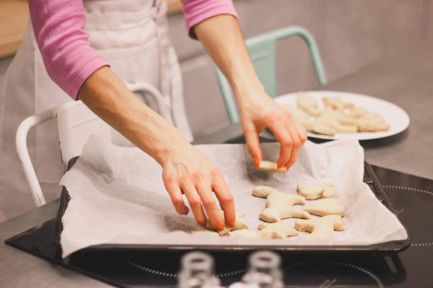 istock Woman's hands place raw ginger cookies on baking tray 1289367732