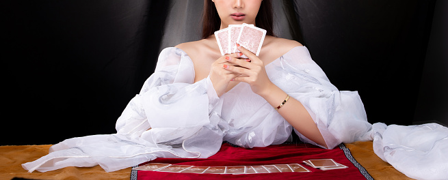 beautiful young girl is sitting at a poker table with cards in her hands. poker game of chance. woman's hands hold poker cards