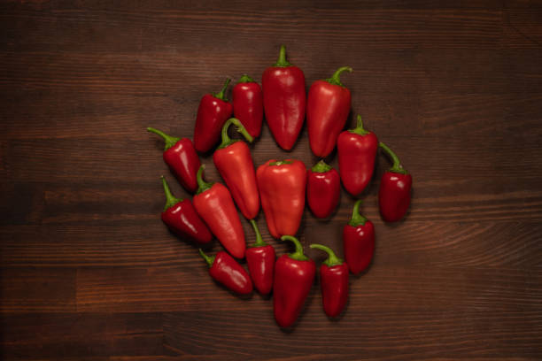 um monte de pimentas e capsicums ou pimentões. sino doce, páprica, caiena, pimenta de cera húngara, isolada no fundo da mesa de madeira. vista superior - birds eye chilli - fotografias e filmes do acervo