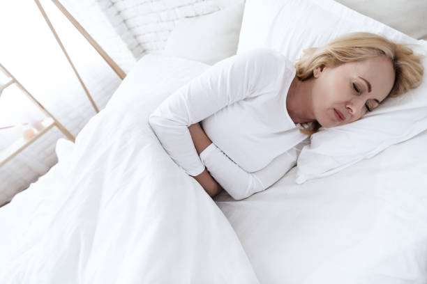 istock A white woman has a stomach ache lying in bed. 1289371605
